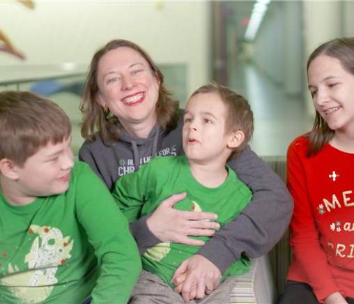 Woman and three kids sitting and smiling together