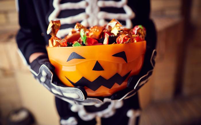 Child holding a bowl of Halloween candy