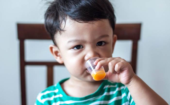 Child drinking medicine from small cup