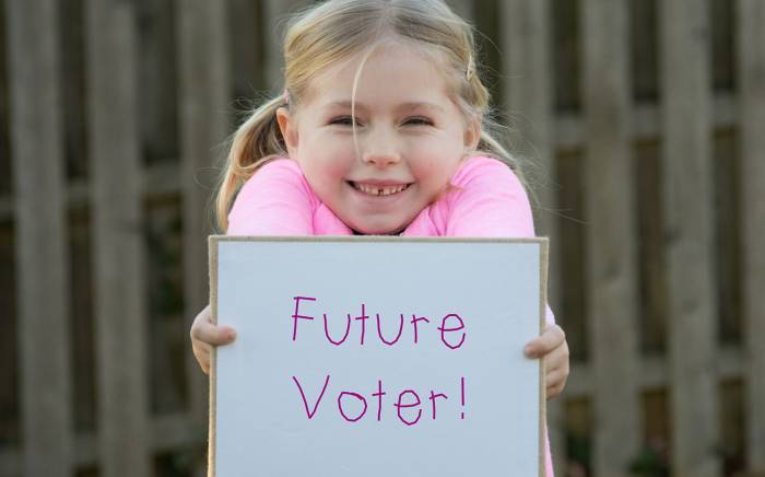 Child holding a "Future Voter!" sign