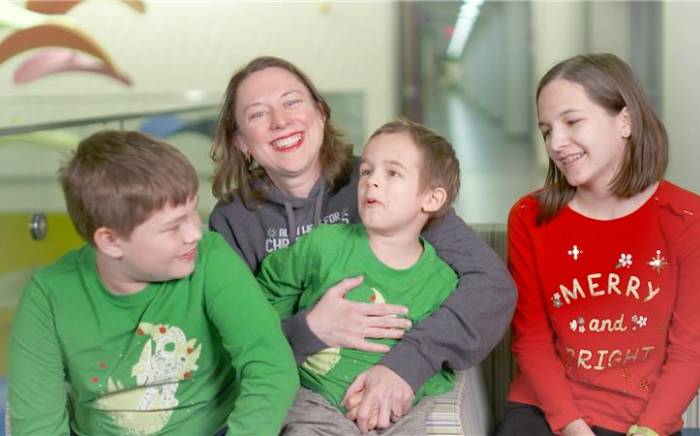 Woman and three kids sitting and smiling together